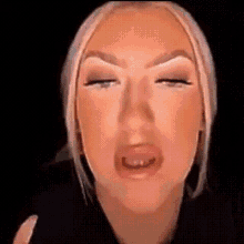 a close up of a woman 's face with her eyes closed and a black background .