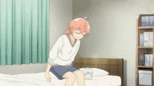 a girl with pink hair is sitting on a bed
