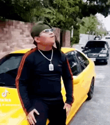 a man is standing next to a yellow sports car .