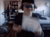 a man wearing sunglasses and headphones stands in a bedroom