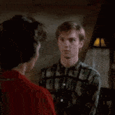 a man in a plaid shirt is talking to a woman