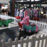 a white picket fence surrounds a play area in a shopping mall
