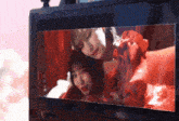 two women in red dresses are shown on a monitor