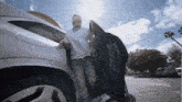 a man in a mask is getting out of a silver car
