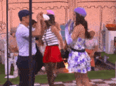a woman in a floral dress is dancing with a man in a blue hat