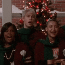 a group of people are standing in front of a christmas tree .