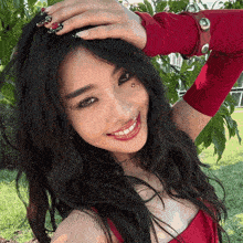 a woman in a red top is smiling and holding her hand to her head