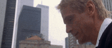 a man in a striped shirt stands in front of a cityscape