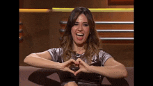 a woman making a heart shape with her hands while smiling