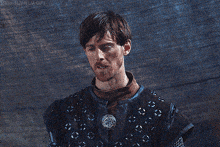 a man with a beard is wearing a blue and brown costume with chain mail