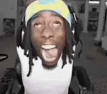 a man wearing headphones and a headband is sitting in a chair with his mouth open .