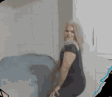 a woman in a black dress is sitting on a bed in a bathroom .