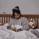 a woman in a striped shirt is laying in bed
