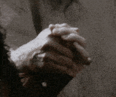 a person is praying with their hands folded in front of a wall