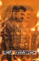 a man with a beard is standing in front of a fire with the name vasik written on the bottom .