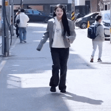 a woman is walking down a sidewalk wearing a jacket and a hoodie that says " always " on it