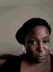 a woman wearing a black hat and earrings is making a face