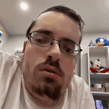 a man with a beard and glasses is taking a selfie in a living room .