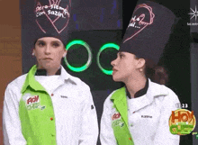 two women wearing chef hats are standing next to each other and looking at each other .