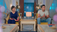 a man and a woman sit in chairs in a living room looking at each other