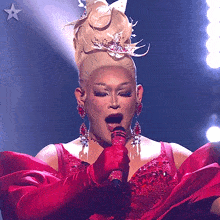 a woman in a red dress singing into a microphone with a star in the background