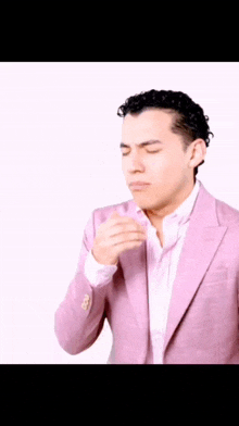 a man in a pink suit and white shirt is coughing