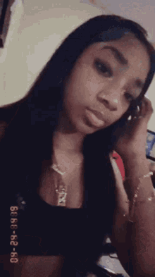 a woman with long black hair is taking a selfie with a cell phone in her hand .