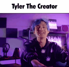 a man with blue hair is smiling in front of a purple wall and says tyler the creator