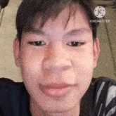 a close up of a young man 's face with a black shirt on .