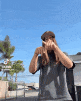 a man with long hair is wearing a hat and making a thumbs up sign with his hands .