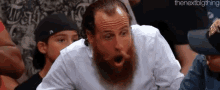 a man with a beard is making a surprised face in a crowd of people