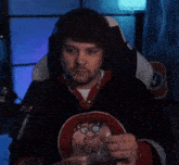 a man is sitting in a chair in front of a microphone and eating a sandwich .