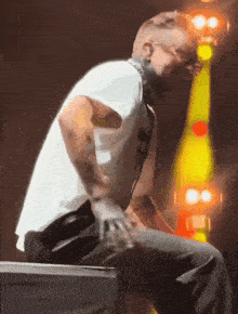 a man in a white shirt and black pants is sitting on a stage