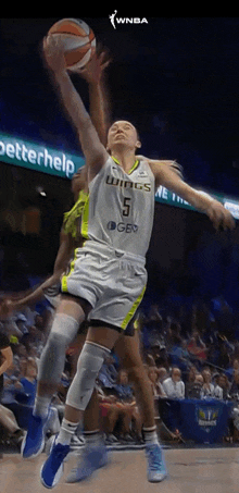 a female basketball player with the number 5 on her jersey jumps for the ball