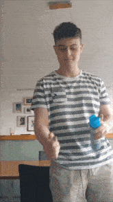 a young man in a striped shirt is holding a bottle