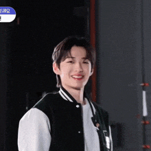 a young man wearing a black and white jacket and a white shirt is smiling .