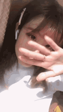a girl is covering her face with her hand while wearing headphones
