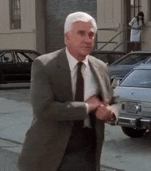 a man in a suit and tie walks down a street