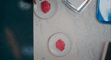 two white plates with red frosting on them on a table