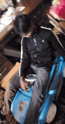 a man is sitting on a blue toy car