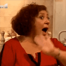 a woman with a surprised look on her face is wearing a red shirt .