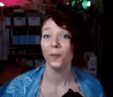 a woman in a blue shirt is making a funny face while looking at the camera .