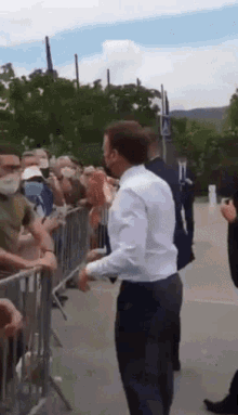 a man in a white shirt is standing in front of a crowd of people wearing masks