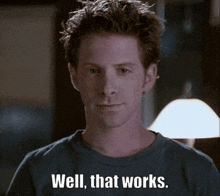 a man in a blue shirt says well that works in front of a lamp
