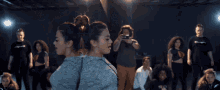 a group of people are dancing in a dark room and one of them is wearing a champion t-shirt