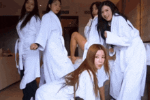 a group of women in bathrobes are posing for a picture in a hotel room .
