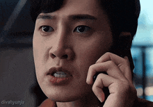 a close up of a person talking on a cell phone with divahyunju written below it