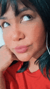 a close up of a woman 's face with a red shirt and black hair