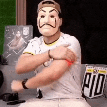a man wearing a mask is sitting on a couch with his arms crossed .