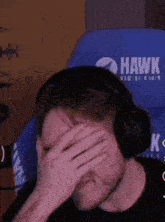 a man wearing headphones covering his face with his hand